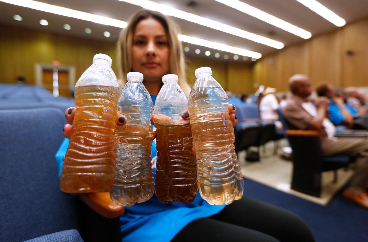 La residente Lucía Camacho muestra botellas con el agua que recibe en su vivienda. / Foto: Aurelia Ventura. 