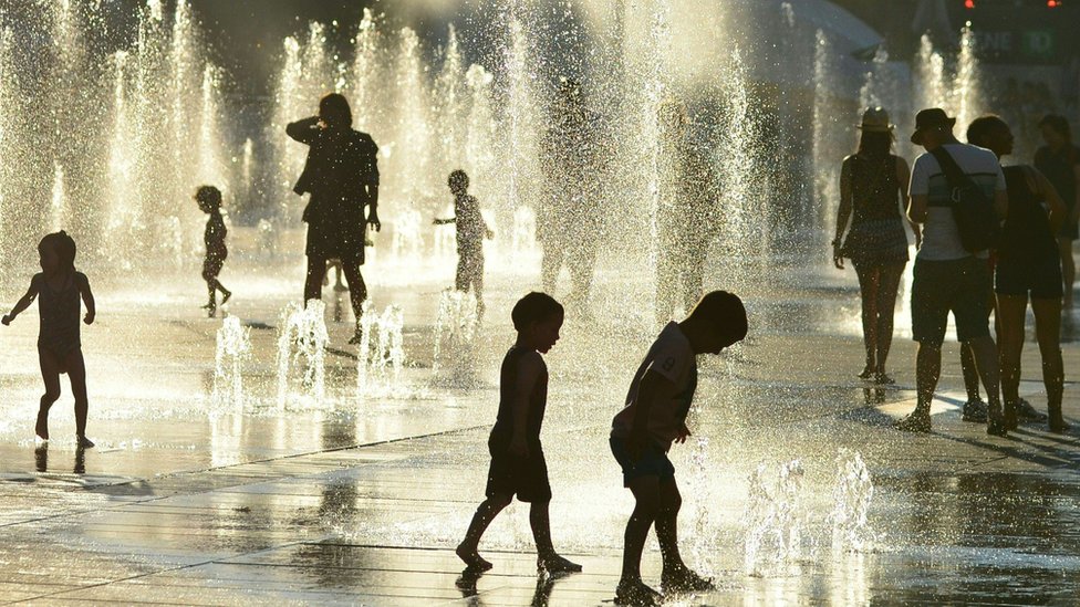 Niños juegan con agua para combatir el calor en Montreal.