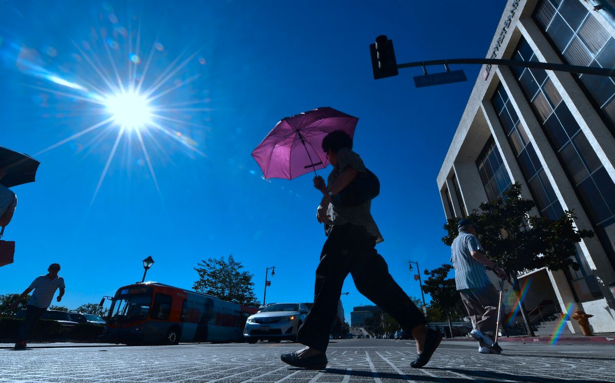 Un peatón utiliza un paraguas para protegerse del sol en Los Ángeles. 
