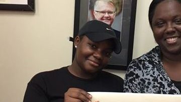 Triticia Crowley (i) muestra el cheque del  premio de la Lotería de Florida.