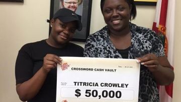 Triticia Crowley (i) muestra el cheque del  premio de la Lotería de Florida.