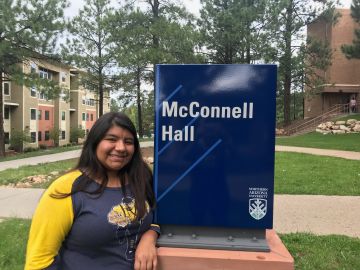 Kaila posa feliz al lado del edificio de dormitorios donde va a vivir mientras estudia en la Universidad del Norte de Arizona. (Foto cortesía abogada Rosa Elena Sahagún)