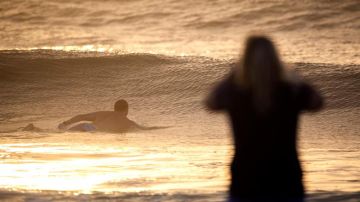 Un hombre surfea las olas en el Océano Atlántico en la playa Wrightsville en Carolina del Norte, estado que espera el azote de Florence.