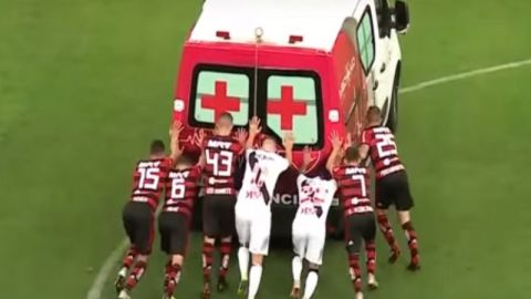 Jugadores del Flamengo y el Vasco da Gama empujan una ambulancia en la cancha.