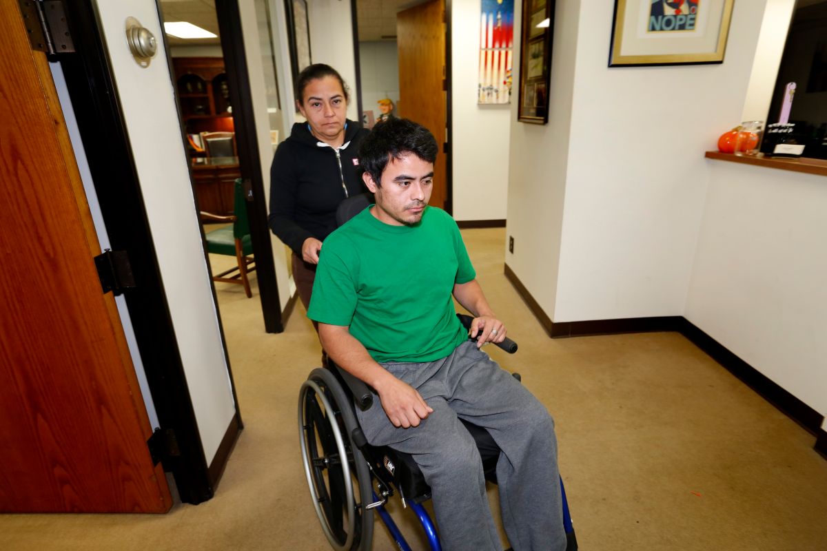 Maritza Márquez empuja la silla de ruedas de Osmin Francisco Pereira en las oficinas del abogado Alex Gálvez.  (Aurelia Ventura/ La Opinion)