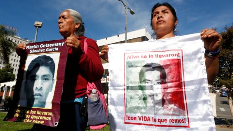 Cristina Bautista y Joaquina García posan con fotos de sus hijos, Benjamín Ascencio Bautista y Martín Getsemaní Sánchez García durante un plantón frente al Consulado de México en Los Ángeles.  (Aurelia Ventura/La Opinion)