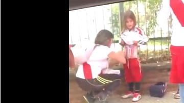 Una aficionada del River Plate coloca luces de bengala en el cuerpo de una niña