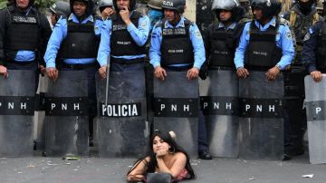 Una manifestante se acuesta frente a la policía en una protesta en Honduras.