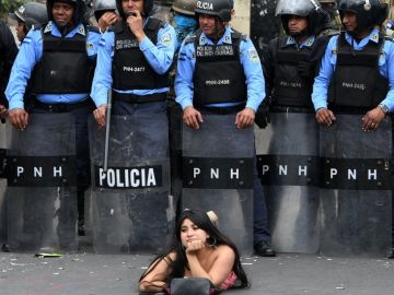 Una manifestante se acuesta frente a la policía en una protesta en Honduras.