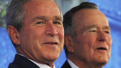 US President George W. Bush (L) and his father George H. W. Bush listen to a patriotic song by country music performers The Gatlin Brothers during the dedication of the new US embassy on August 8, 2008 in Beijing. US President George W. Bush on August 8 made a new plea for freedom of expression in China as he prepared to attend the opening ceremony of the 2008 Beijing Olympic Games later in the day. AFP PHOTO / Mandel NGAN (Photo credit should read MANDEL NGAN/AFP/Getty Images)