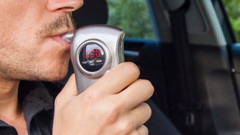 Un hombre sopla en un alcoholimetro antes de encender su auto. (Getty Images)