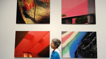 Un visitante pasa cerca de fotografías sobre metal instaladas en el Museo de Arte Contemporaneao (MOCA).