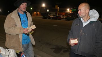 Lawlond Arnold, un desamparado nacido en Georgia conversa con su amigo Charles Hubbard, quien le regaló una hamburguesa para mitigar el hambre. (Jorge Luis Macias, Especial para La Opinión)