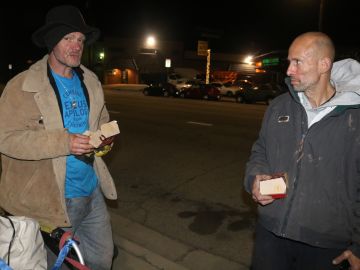 Lawlond Arnold, un desamparado nacido en Georgia conversa con su amigo Charles Hubbard, quien le regaló una hamburguesa para mitigar el hambre. (Jorge Luis Macias, Especial para La Opinión)