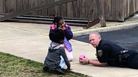 Un policía juega con una niñas para que le pierdan el miedo.