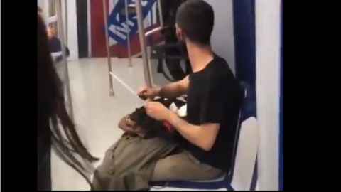 Un usuario de Metro de Madrid afila un cuchillo en el tren.