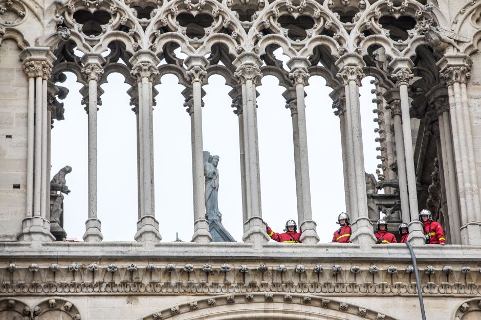 Bomberos permanecen entre las columnas de la catedral de Notre Dame este martes.