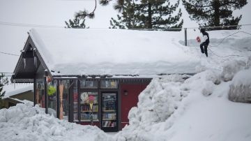 Una persona remueve la nieve del techo de una casa en enero del 2017 cuando una serie de fuertes tormentas de nieve llegó a la zona este de California.
