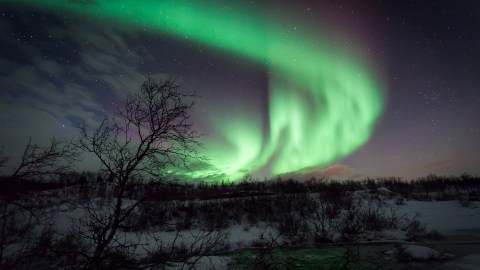 La aurora boreal es causada por ondas de partículas emitidas por el Sol.