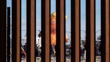 Un globo satírico de un bebé del presidente de los Estados Unidos, Donald Trump, es visto a través de la valla fronteriza entre Estados Unidos y México durante una manifestación contra él durante su visita a Calexico.
