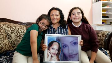 Alma Ramirez sostiene una fotografía de su hija, junto a sus nietas Alina y Aaliyah. / foto: Aurelia Ventura.