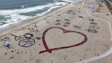Estudiantes de Los Ángeles forman una figura en la playa, después de limpiarla.
