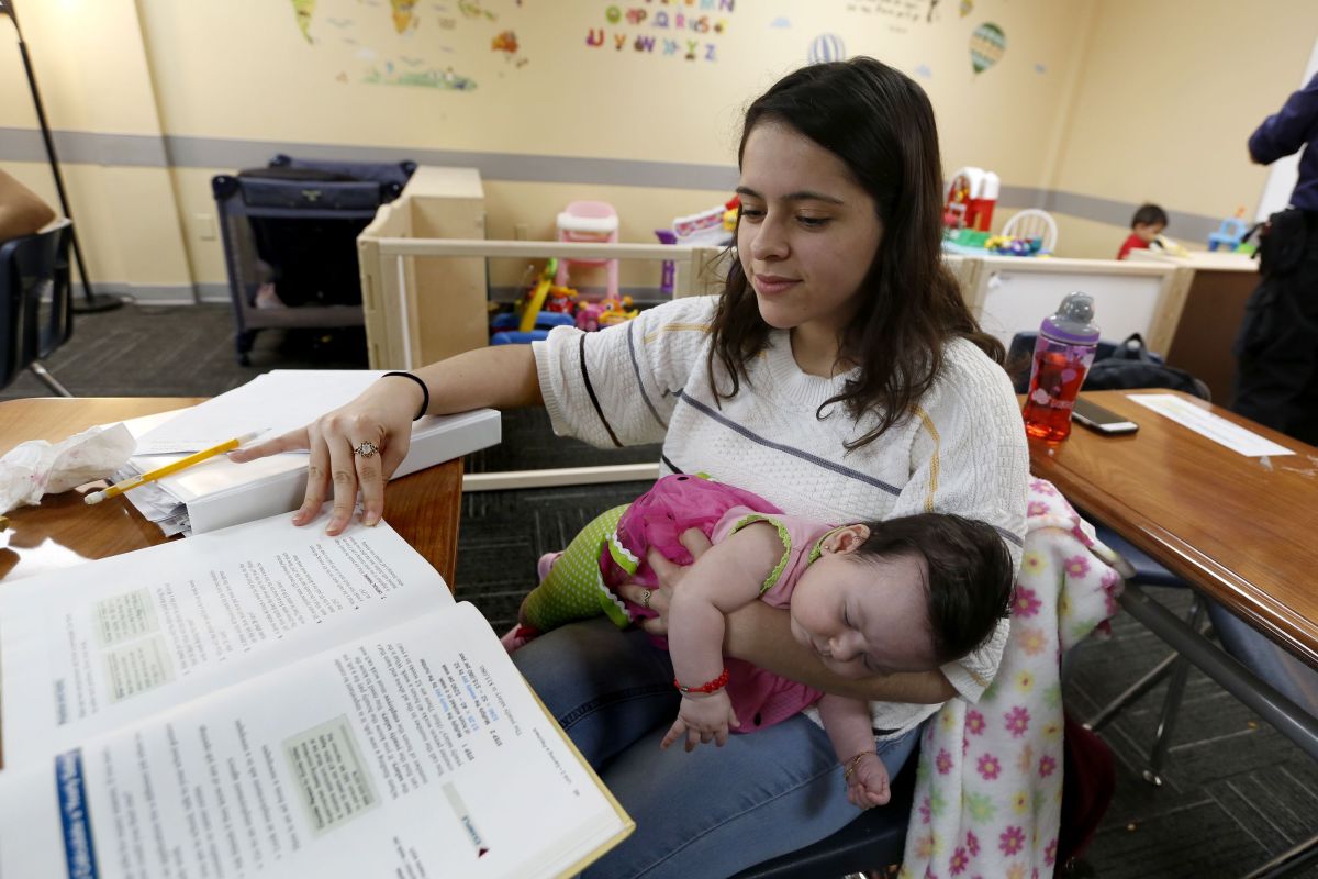 Lidia Mayhew carga a su bebita de 3 meses mientras estudia y hace sus tareas de la escuela. / foto: Aurelia Ventura. 