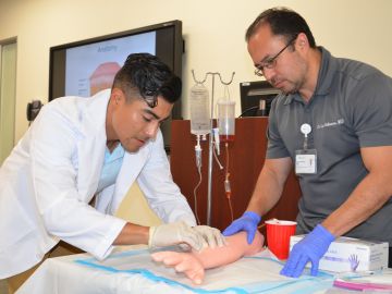 Harvey Peralta, 26, (izq.) practica como poner inyecciones en el programa de verano HCOP de AltaMed y la Universidad Charles Drew. (Suministrada)