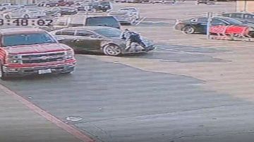 En el video se puede observar el vehículo en el estacionamiento con el oficial sobre el cofre.
