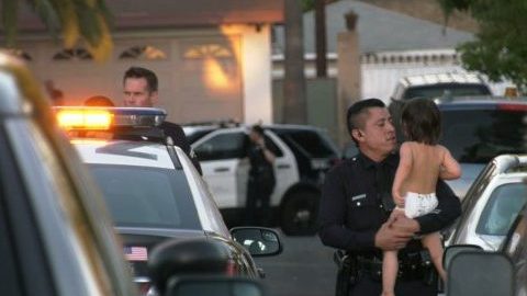 Un policía sostiene en sus brazos al bebe quien se encuentra bajo custodia de las autoridades.