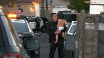 Un policía sostiene en sus brazos al bebe quien se encuentra bajo custodia de las autoridades.