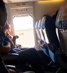 Una mujer abre la puerta de emergencia durante un vuelo.