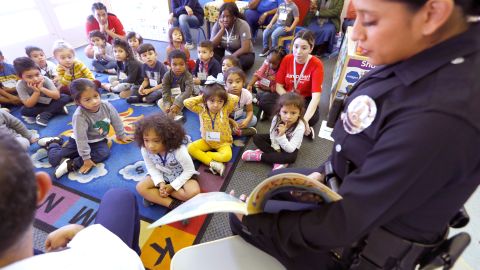 La agente del LAPD, Alma Martínez, lee a los alumnos de la escuela Hoover Intergenerational Care.  (Aurelia Ventura/La Opinión)