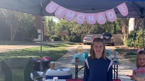 Las niñas venden limonada y otros productos para recaudar fondos.