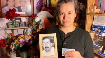 Magdalena Gómez  sostiene su tarjeta de residente en una mano, y en la otra la foto de su esposo, quien a causa de su repentino fallecimiento durante los trámites de residencia, no la pudo obtener. (Araceli Martínez/La Opinión).