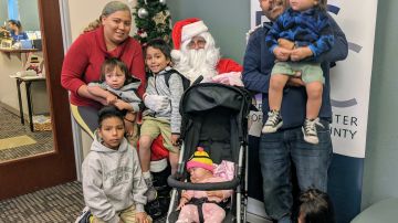 Reina Rocha y Eusebio Morales junto a seis de sus nueve hijos listos para recibir los regalos de Santa Claus. (Jacqueline García/La Opinión)