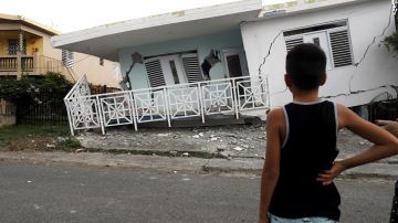 Un niño observa una casa dañada por el temblor en Puerto Rico.