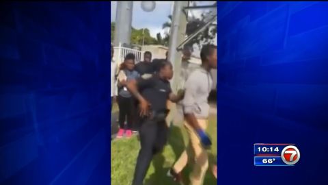 Momento del video en el que aparece la mujer entre los estudiantes y tocando la funda de su arma.