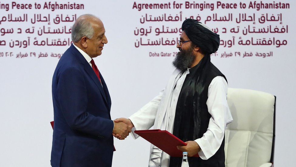 Zalmay Khalilzad da la mano al cofundador del Talibán, Mullah Abdul Ghani Baradar, durante la firma del acuerdo .