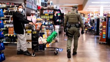 Un alguacil patrulla un supermercado en Los Ángeles, para que se mantenga el distanciamiento social.