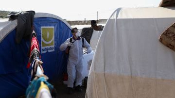Personal sanitario desinfecta un campamento de desplazados por la guerra.