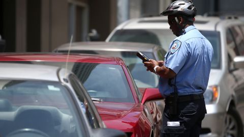 Oficial emite multa a un vehículo estacionado.