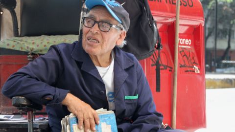 Benigno Hernández lee la biblia mientras espera que alguien quiera bolearse los zapatos en medio de la contingencia por coronavirus.