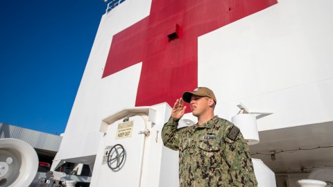 Un oficial de la Marina haciendo un saludo a la bandera a bordo del USNS Mercy.