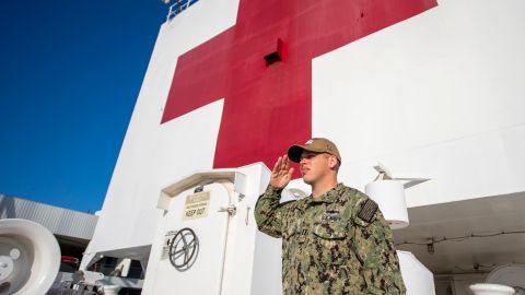 Un oficial de la Marina haciendo un saludo a la bandera a bordo del USNS Mercy.