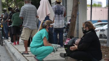 Una enfermera junto a una persona sin hogar en el centro de Miami.