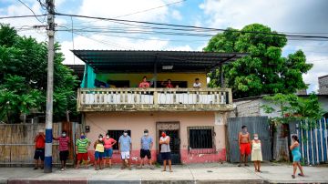 Vecinos de un fallecido en la ciudadela Bastión Popular en Guayaquil (Ecuador), observan a los policías ecuatorianos que forman parte del equipo de la Fuerza de Tarea Conjunta (FTC), para la recolección de los cadáveres en medio de la pandemia del COVID-19. EFE/Mauricio Torres/Archivo