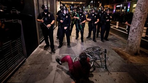 Una mujer cae de su bicicleta mientras la Policía de L.A. le bloquea el paso.