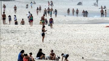Decenas de personas disfrutan de la playa de Brarra de tijuca este viernes, pese a que las autoridades en la ciudad han pedido a los ciudadanos respetar las medidas de aislamiento por la pandemia de coronavirus, en Río de Janeiro (Brasil). EFE/Antonio Lacerda