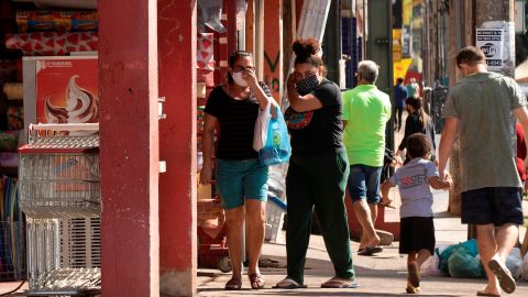 Habitantes de Brasilia, con cubrebocas, hacen sus compras sabatinas en una calle de esta ciudad.